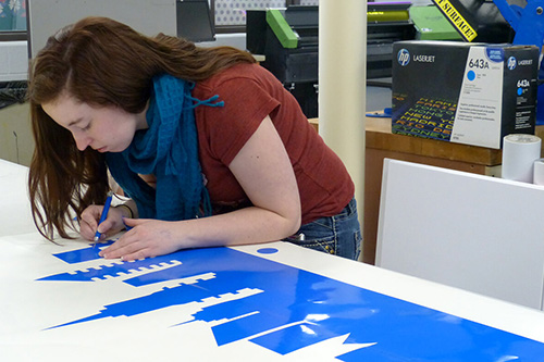 A student cuts vinyl for an installation