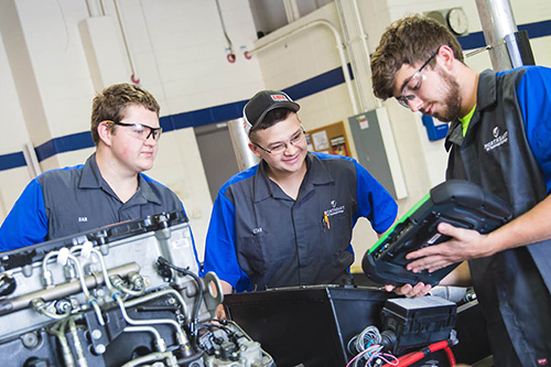 Three students work on a diesel truck