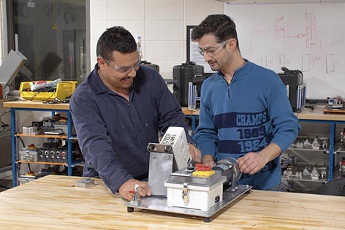 Two students work on industrial components