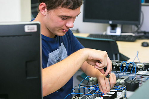 A student works on a circuit board in a classroom