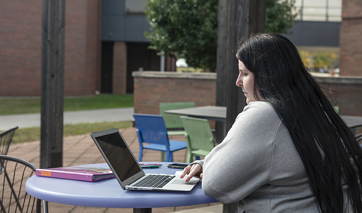 A student uses a laptop on the library patio