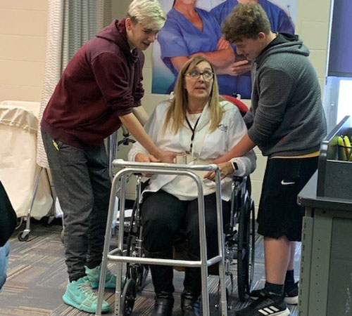 Woodland students help a patient in a walker