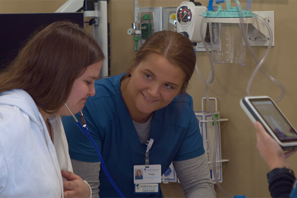 A high school student listens to the heartbeat of a patient simulator