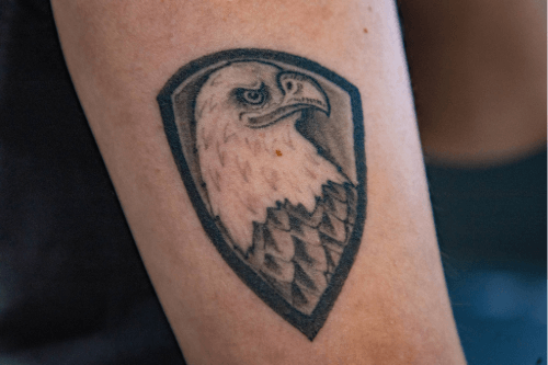 Close up of an eagle tattoo within a shield on an arm.