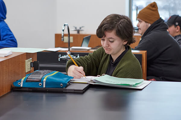 A high school student takes notes in a lab classroom