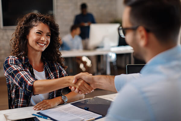 A young student shakes the hand of her interviewer