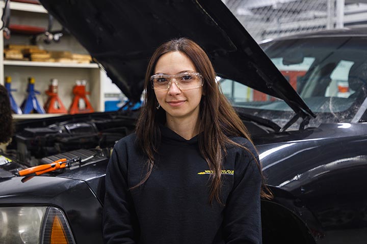 Female student wears a mask and works on a cnc machine tool 