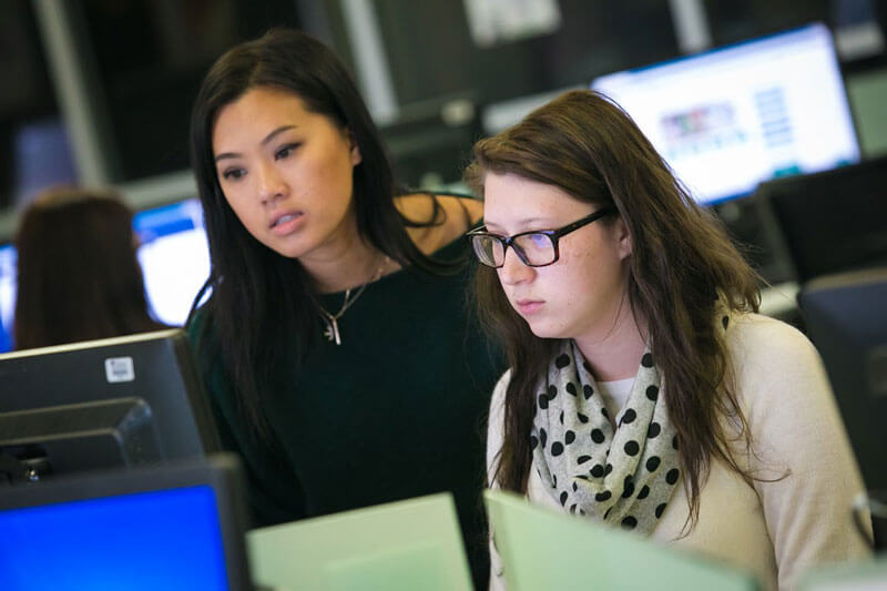 An advisor works with a student on a computer