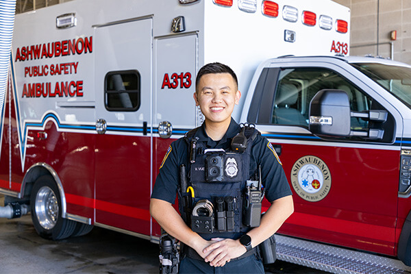Victor Vue stands in uniform in front of an ambulance