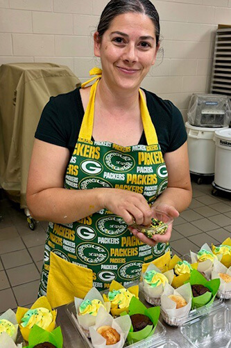 Krissie from Little Miss Addie Cupcakes adds toppings to her products